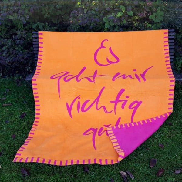 Kuscheldecke von Signs by Jwala in orange und pink mit dem Sign 'Es geht mir richtig gut'